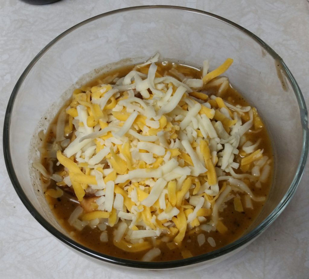 Soup with bagel and shredded cheese.