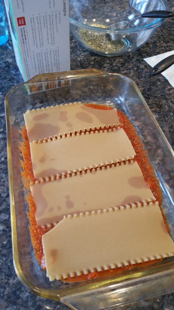 Initial layers of sauce and noodles