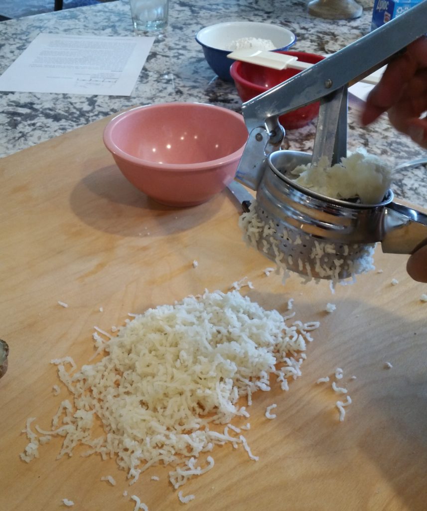 Diane is using the potato ricer to prepare the baked potato for the dough.