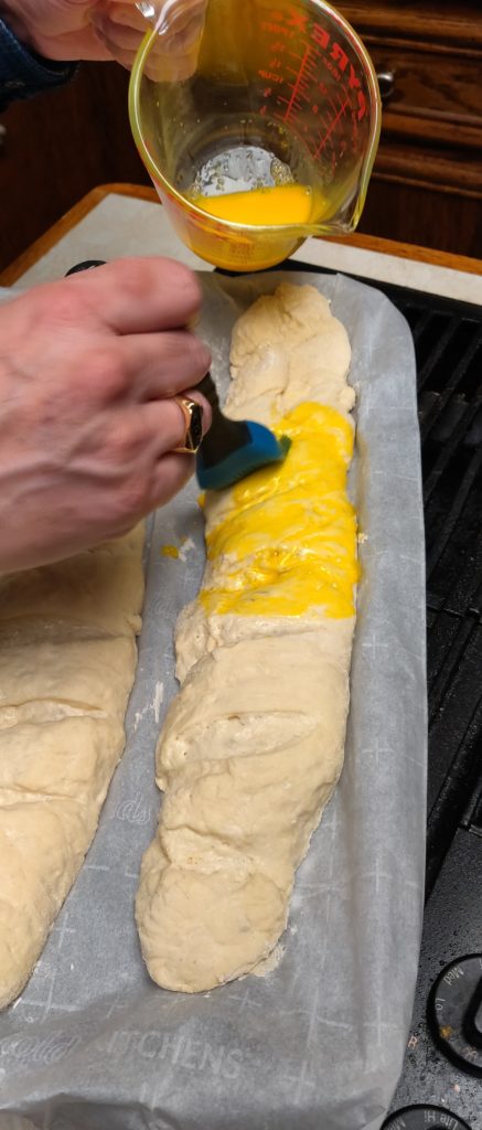 Applying the egg wash after the second rising of the dough.